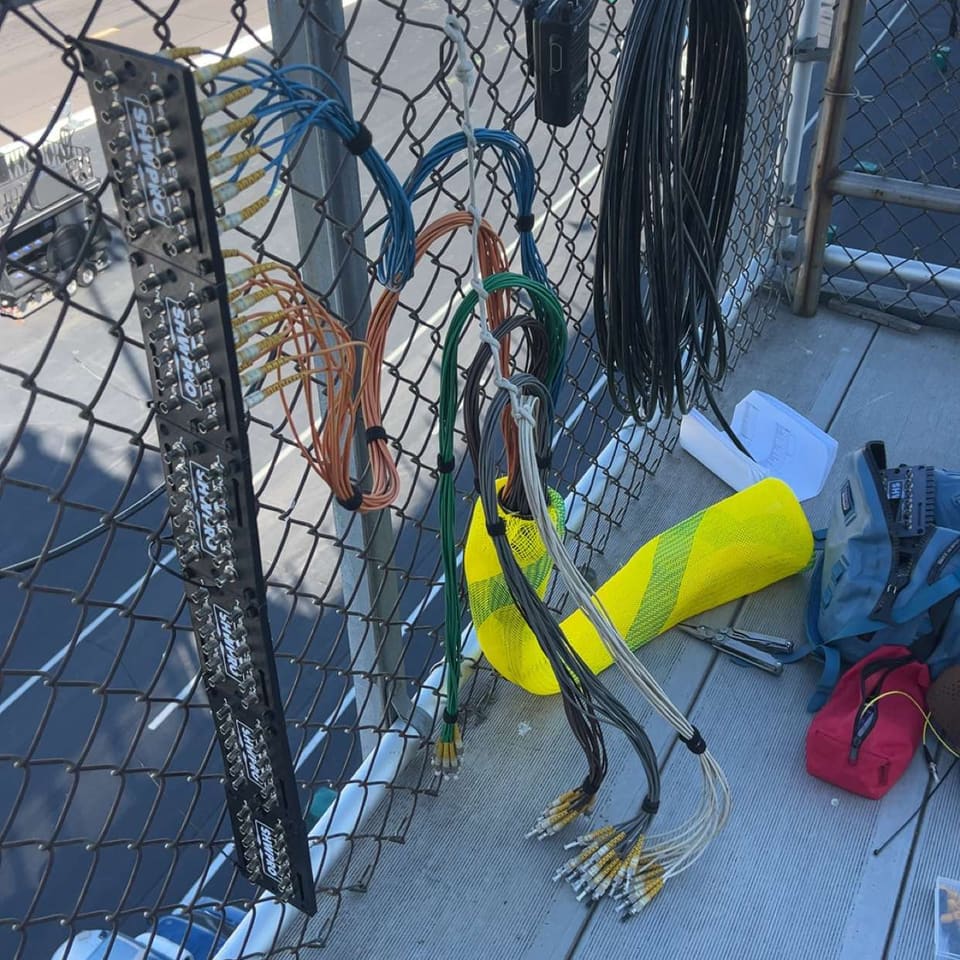 ST Patch Panel on a fence with fiber runs and yellow sleeving at the base