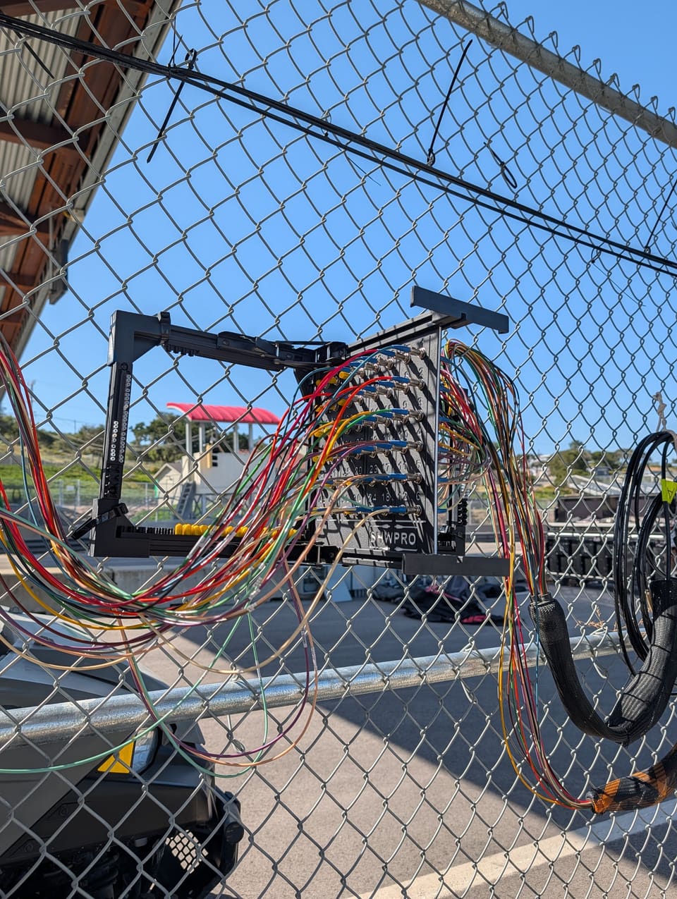 The Frame zip tied to a chain link fence with fiber runs patched in